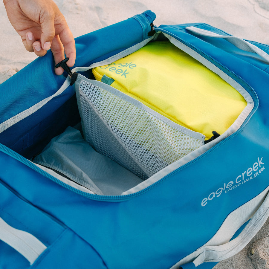 A yellow packing cube inside of a blue duffle bag
